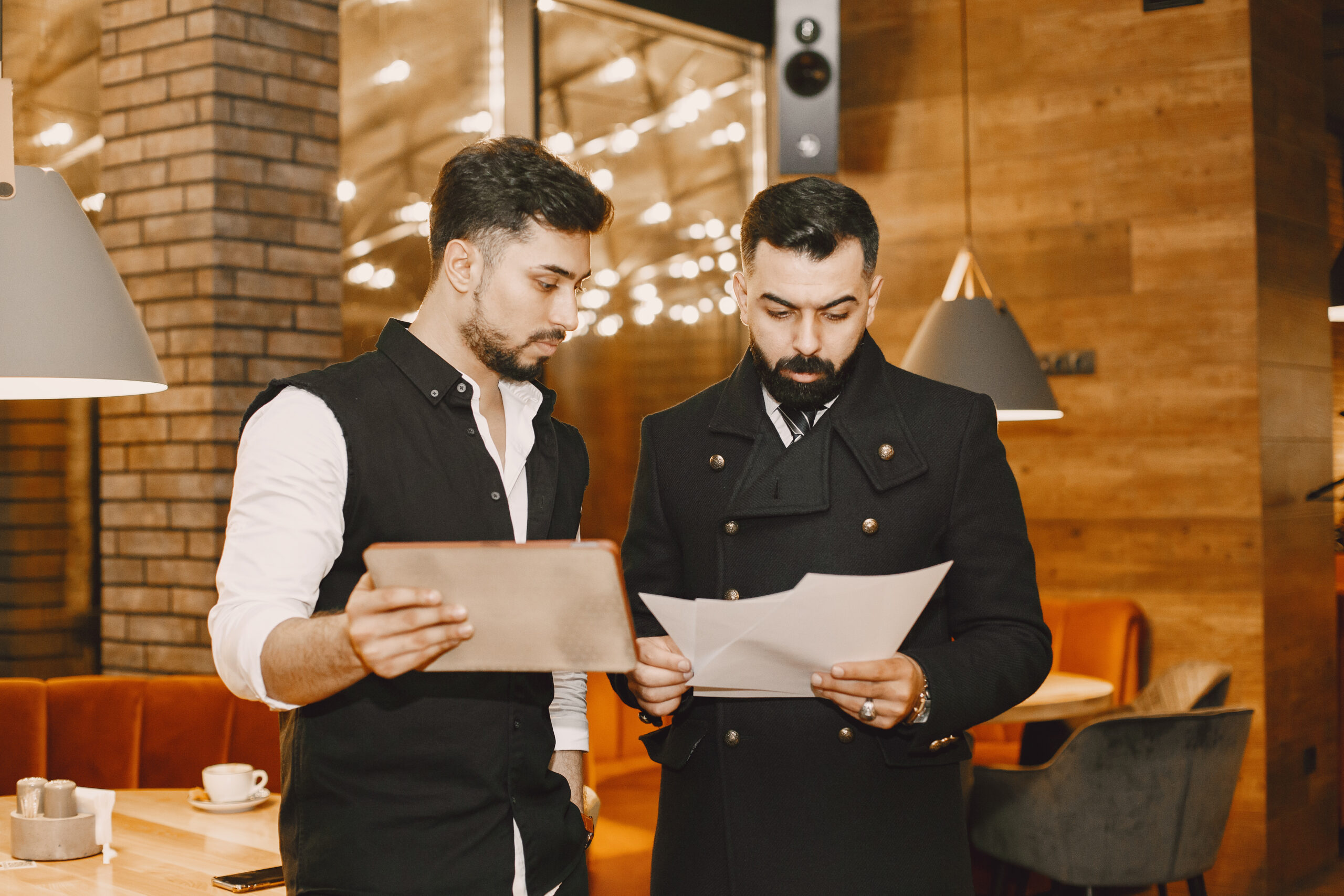 Handsome man in a black suit. Businessmen working in a cafe. People stands and looks in a documents.
